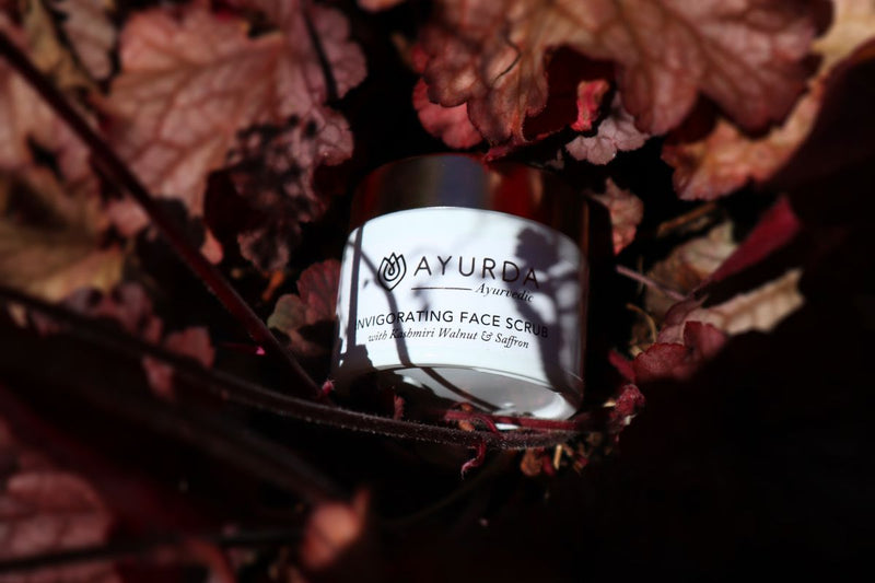 Ayurda invigorating scrub nestled in a pile of burgundy autumn leaves