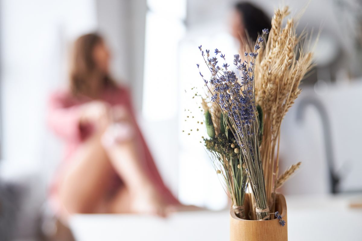 dried flowers in focus in the foreground, women in blurred background about to indulge in an at home spa day