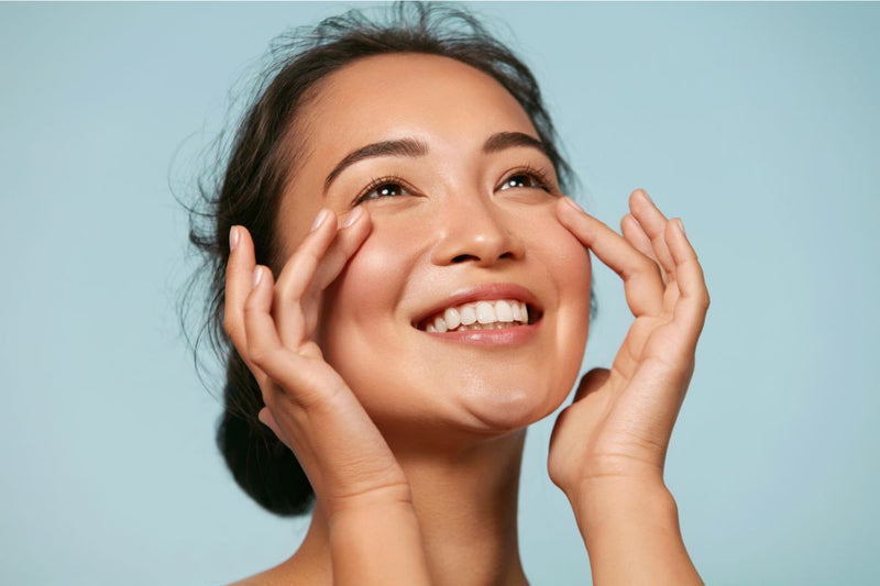 woman touching her cheeks revealing hydrated glowing skin